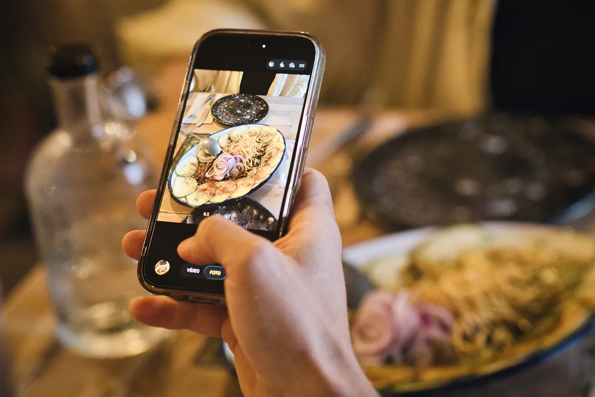 Un ospite fotografa un piatto con il telefono
